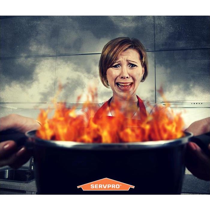 A lady holding a burning in flames cooking pot